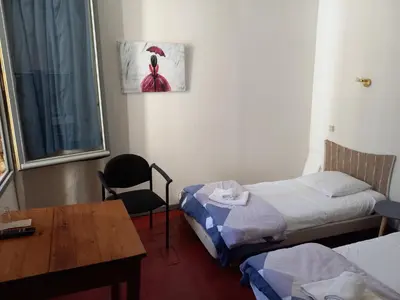 a room with two beds and a table and a chair at Hôtel Du Cours in Pertuis