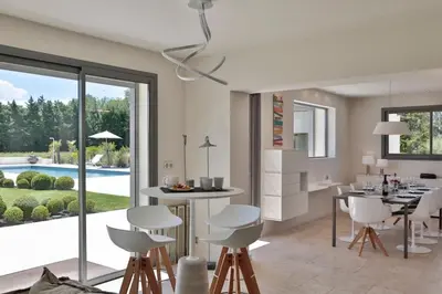 a kitchen with white chairs and a dining room with a pool at Mas de Panière - Saint Remy de Provence in Paluds de Noves
