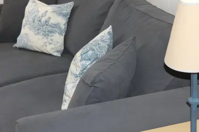 a gray couch with two blue and white pillows at Logis Hotel le Mas De Cure Bourse in LʼIsle-sur-la-Sorgue