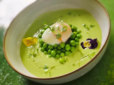 a bowl of green food with peas and flowers at Logis Hotel le Mas De Cure Bourse in LʼIsle-sur-la-Sorgue