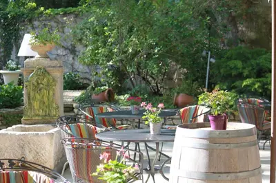 an outdoor patio with tables and chairs and plants at Logis Hotel le Mas De Cure Bourse in LʼIsle-sur-la-Sorgue
