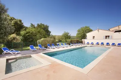 a swimming pool with lounge chairs and a swimming pool at Résidence Odalys Les Soleils du Luberon in Bonnieux