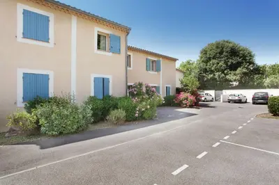 a building with blue doors in a parking lot at Résidence Odalys Les Soleils du Luberon in Bonnieux