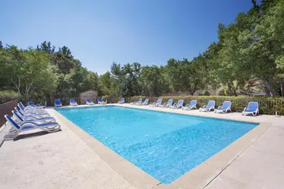 a swimming pool with lounge chairs and a swimming pool at Résidence Odalys La Bastide des Chênes in Gordes