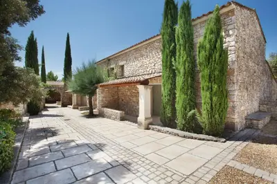 a stone building with trees in front of it at Résidence Odalys La Bastide des Chênes in Gordes
