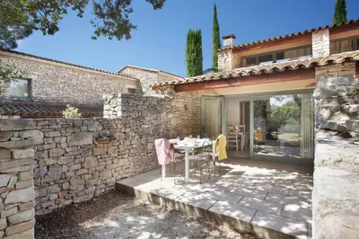 a patio with a table and a stone wall at Résidence Odalys La Bastide des Chênes in Gordes