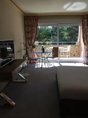 a living room with a bed and a table and a balcony at Hostellerie Le Roy Soleil in Ménerbes