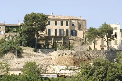 a building on top of a hill with trees at Hostellerie Le Roy Soleil in Ménerbes