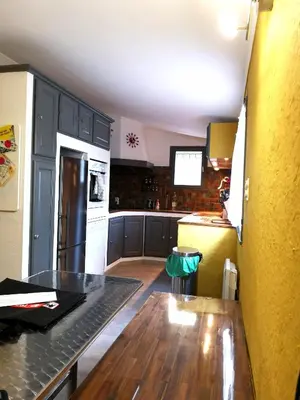 a kitchen with black cabinets and a wooden table at Maison le Pastaga in Caromb