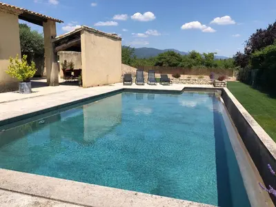 a swimming pool with blue water in a yard at Villa dans le LUBERON à 2 km de LOURMARIN in Lauris