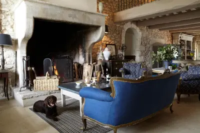 a living room with a blue chair and a fireplace at La Bastide de Marie, Maisons et Hôtels Sibuet in Ménerbes