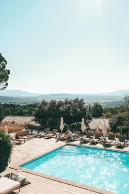 a swimming pool with chaise lounge chairs next to a resort at Mas des Herbes Blanches Hôtel & Spa – Relais & Châteaux in Joucas