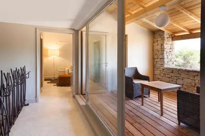 a living room with a wooden deck with a table at Mas des Herbes Blanches Hôtel & Spa – Relais & Châteaux in Joucas