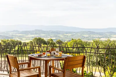 a table with a plate of food and two chairs at Mas des Herbes Blanches Hôtel & Spa – Relais & Châteaux in Joucas