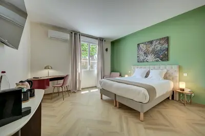 a bedroom with a bed and a desk and a television at Logis Hotel Le Blason de Provence in Monteux