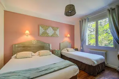 two beds in a room with pink walls and windows at Logis Hotel Le Blason de Provence in Monteux