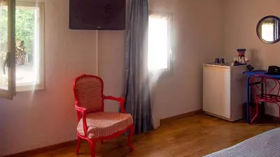 a bedroom with a red chair and a window at Mas du Kairos in Venasque