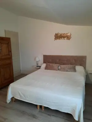 a bedroom with a white bed with a brown headboard at Mas du Kairos in Venasque