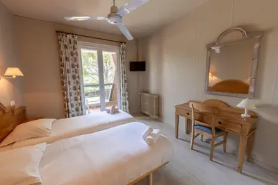 a bedroom with two beds and a desk and a mirror at Vacances Bleues Hôtel Castel Luberon in Apt