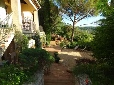 a wooden pathway leading to a house with a tree at Villa Lumières in Goult
