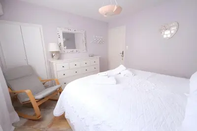a white bedroom with a bed and a chair at Vacation rental in the Alpilles, Provence, close to the village center - Beautiful view -Air conditionning Heated pool and spa - sleeps 8 in Aureille
