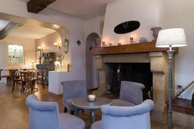 a living room with a fireplace and a table and chairs at Hôtel du Parc, Avignon Est, The Originals City, in Entraigues-sur-la-Sorgue