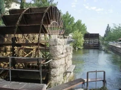 a river with a stone wall next to the water at Hôtel du Parc, Avignon Est, The Originals City, in Entraigues-sur-la-Sorgue