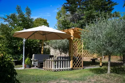 an umbrella and a chair and a bench and a table at L’ocabée in La Tour-dʼAigues