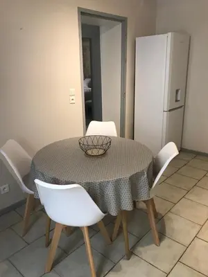 a dining room table with white chairs and a refrigerator at Au cœur de Céreste in Céreste