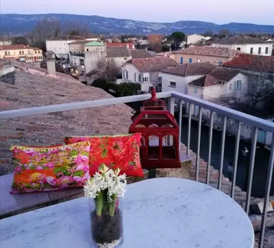 a table with a vase of flowers on a balcony at LE BELVEDERE in LʼIsle-sur-la-Sorgue