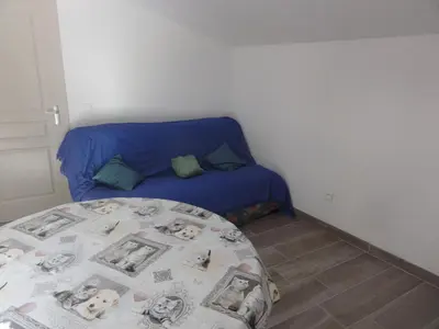 a bed in a room with a blue couch at Gite le bagnol un coin de paradis in Maubec