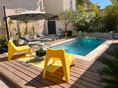 a pool with two yellow chairs and an umbrella at Cosy Studio en Provence in Carpentras