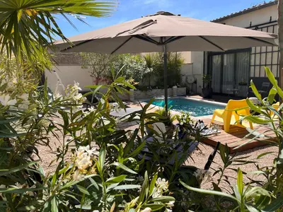 an umbrella and chairs next to a swimming pool at Cosy Studio en Provence in Carpentras