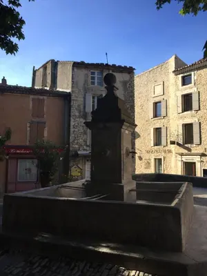 a fountain in the middle of a street with buildings at Chez Marius Gordes Vue panoramique sur luberon in Gordes
