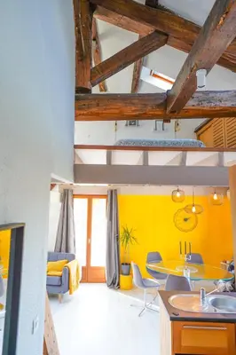 a kitchen and living room with yellow walls and wooden ceilings at Bel appart pour 6 p, clim, parking et terrasse in Aix-en-Provence