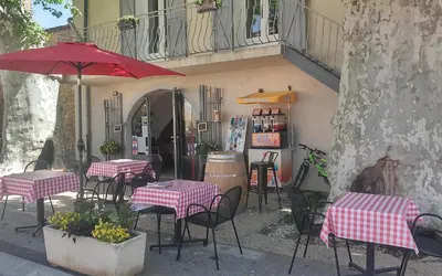 a group of tables and chairs with a red umbrella at Une Chambre en Luberon in Puyvert