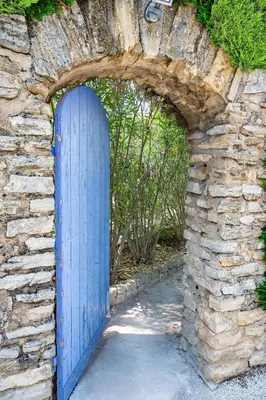 an archway with a blue door in a stone wall at La Pastorale in Lagnes