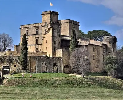 an old castle with a flag on top of it at Maison La Plaine in Lourmarin
