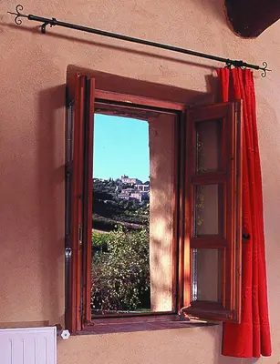 a window with a red curtain on a wall at La Fontaine in Simiane-la-Rotonde