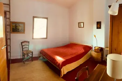 a bedroom with a bed and a chair in it at Stone house in Isle-sur-la-Sorgue in LʼIsle-sur-la-Sorgue