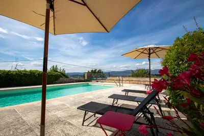 a patio with two chairs and an umbrella and a pool at Chez Manon in Apt