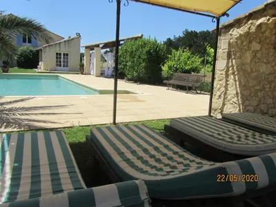 two lounge chairs under an umbrella next to a swimming pool at Maison provençal avec PISCINE in Cavaillon
