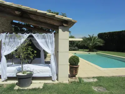 a bed in a gazebo next to a pool at Maison provençal avec PISCINE in Cavaillon