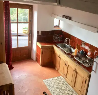 a kitchen with wooden cabinets and a sink and a window at LA MAISON D’ALICE in Sault-de-Vaucluse