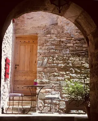 a table and two chairs in front of a stone wall at LA MAISON D’ALICE in Sault-de-Vaucluse