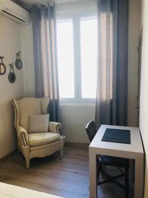 a living room with a chair and a table at Les volets rouges in Cavaillon
