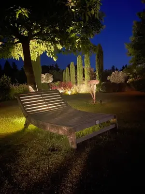 a wooden bench sitting in the grass under a tree at Mas La Pomarede in Robion en Luberon