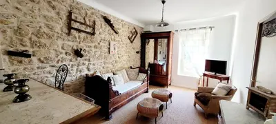 a living room with a couch and a stone wall at Mas La Pomarede in Robion en Luberon