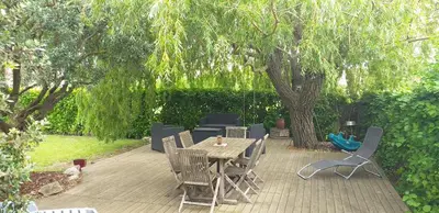 a patio with a table and chairs under a tree at Un petit coin de paradis in Modène