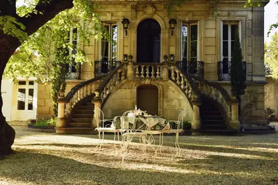 a table in front of a building with a staircase at Embarben Maison d'hôtes in Saint-Chamas